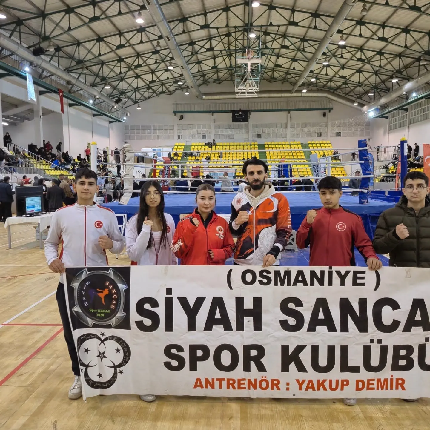Siyah Sancak Spor Kulübü pankartının önünde sporcular ve antrenör