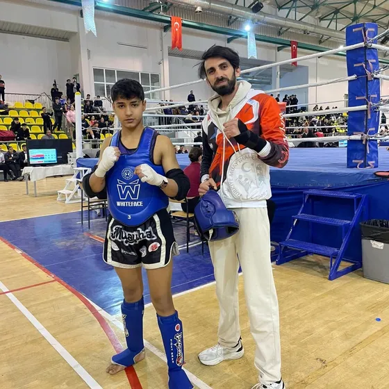 Mavi korumalı sporcu ve antrenör ringin önünde